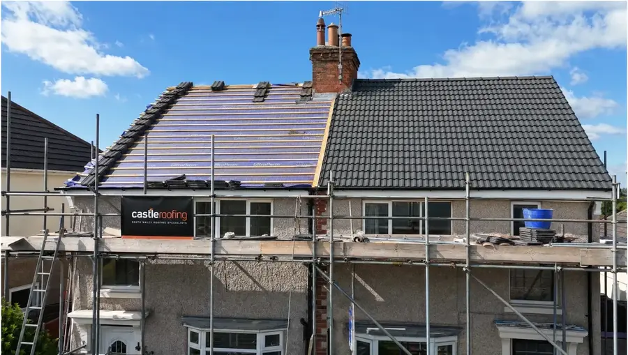 Semi-detached house mid re-roof with half the roof stripped to membrane and half newly tiled