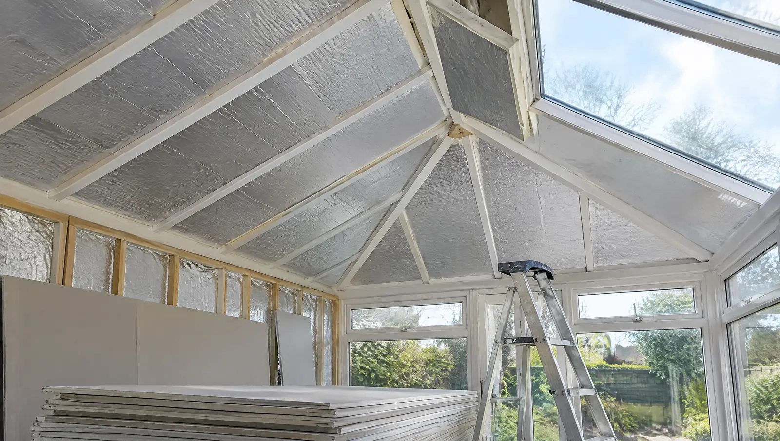 Insulation boards being fitted between timber rafters inside a conservatory mid-conversion