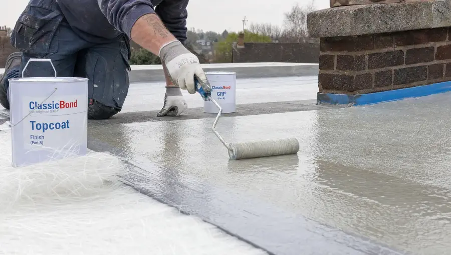 Roofer applying GRP fibreglass resin with a roller