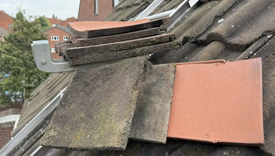 Old weathered roof tile compared with a new replacement tile