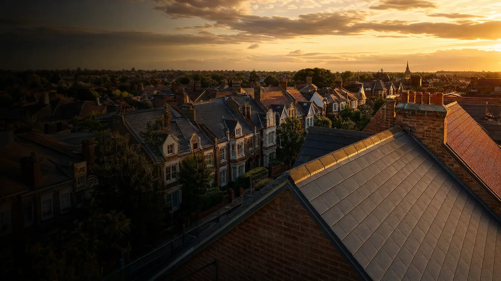 Aerial view of UK rooftops at golden hour with newly installed slate roofs