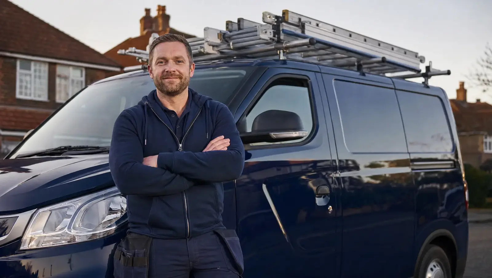 Roofing company owner standing proudly in front of his work van