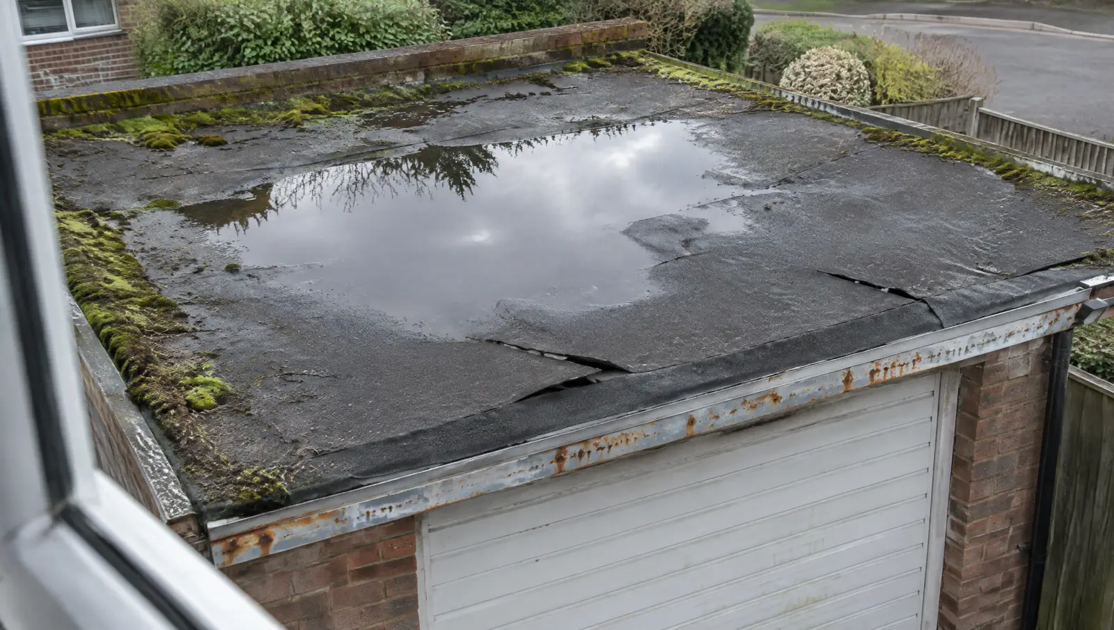 Ageing felt flat garage roof with standing water ponding and split seams
