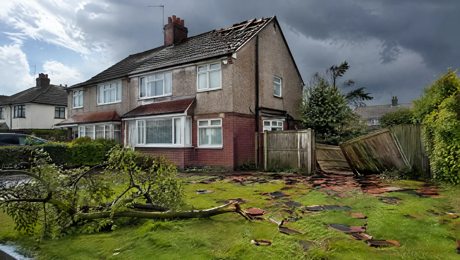 Storm aftermath on a British street with broken roof tiles scattered across a wet lawn