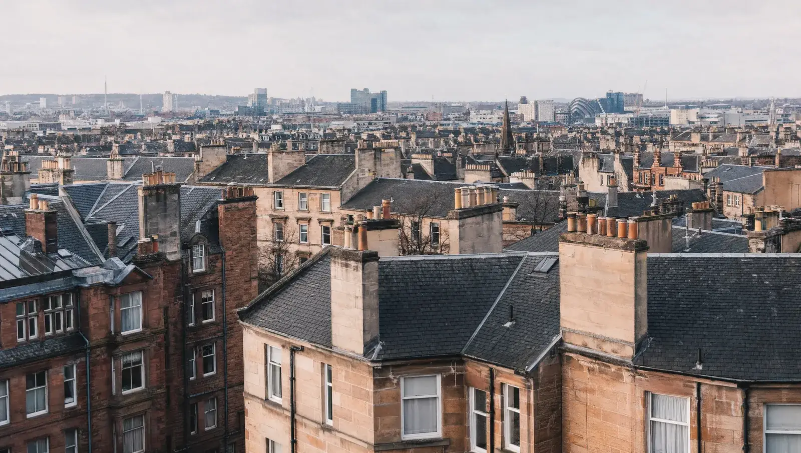 Glasgow sandstone tenement rooftops with grey slate roofs and rows of chimney pots