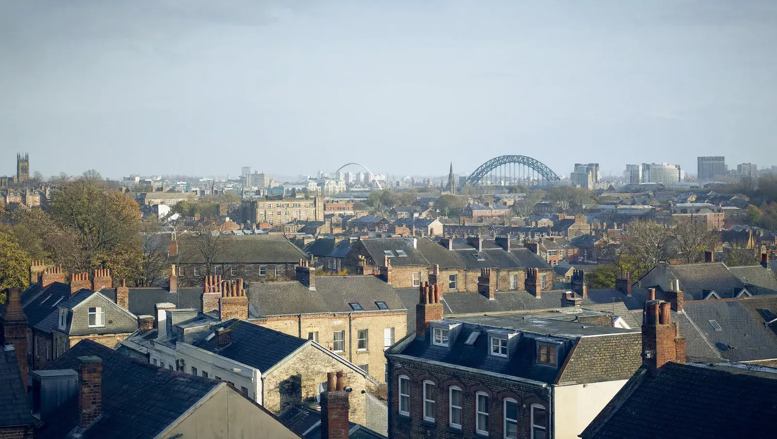 Newcastle terraced rooftops with the Tyne bridges silhouetted in the far distance