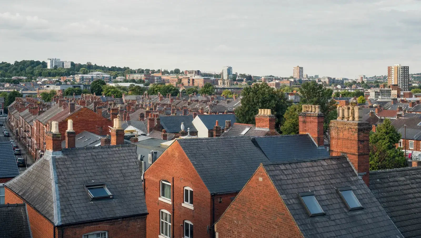 Red-brick Victorian terraced rooftops in Nottingham with slate roofs and chimney stacks