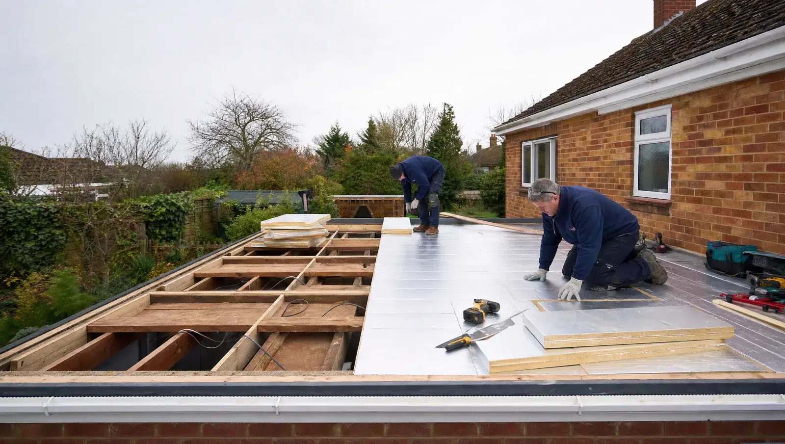 Flat roof stripped to the joists with new insulation boards being laid on a UK extension