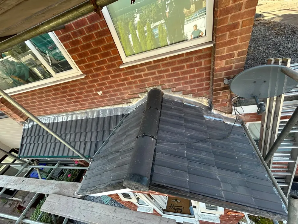 Bay roof re-covered in grey tiles with a new ridge, seen from the scaffold
