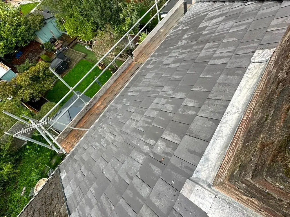 Finished grey slate-effect tile slope with flashing, seen from the scaffold