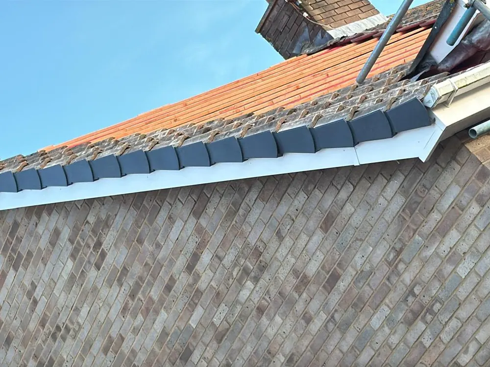 New white fascia, soffit and gutter under a tiled roof edge