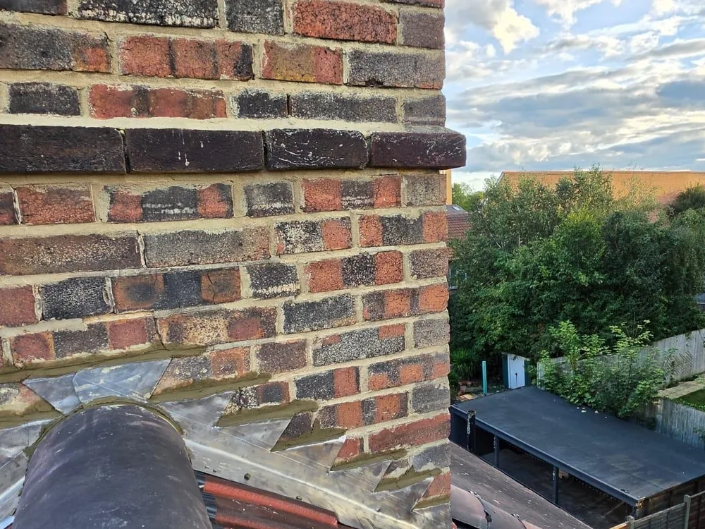Brick chimney stack above a new ridge line on a re-tiled roof