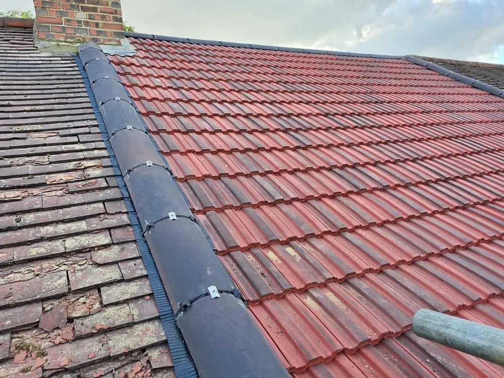 Weathered old tiles beside new red tiles on the same roof slope