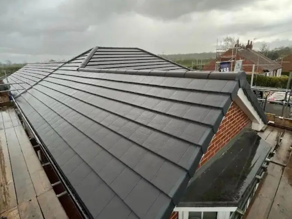 Finished re-roof in grey slate-effect tiles with a new dry verge, scaffold still up