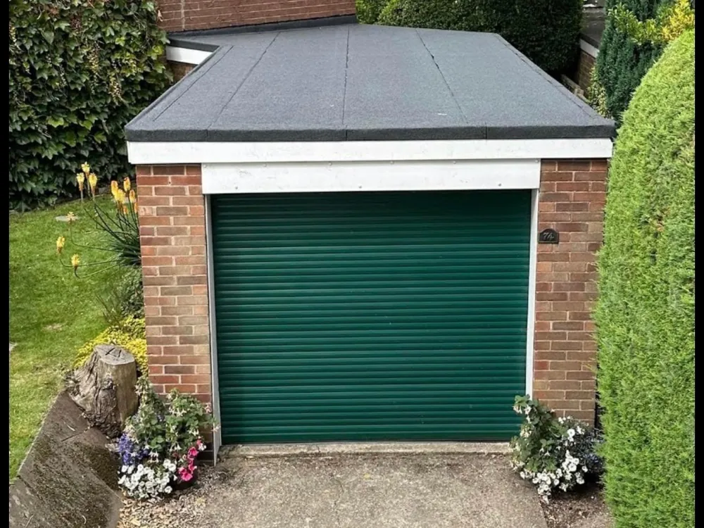 Garage with a new felt flat roof and trims, green roller door below