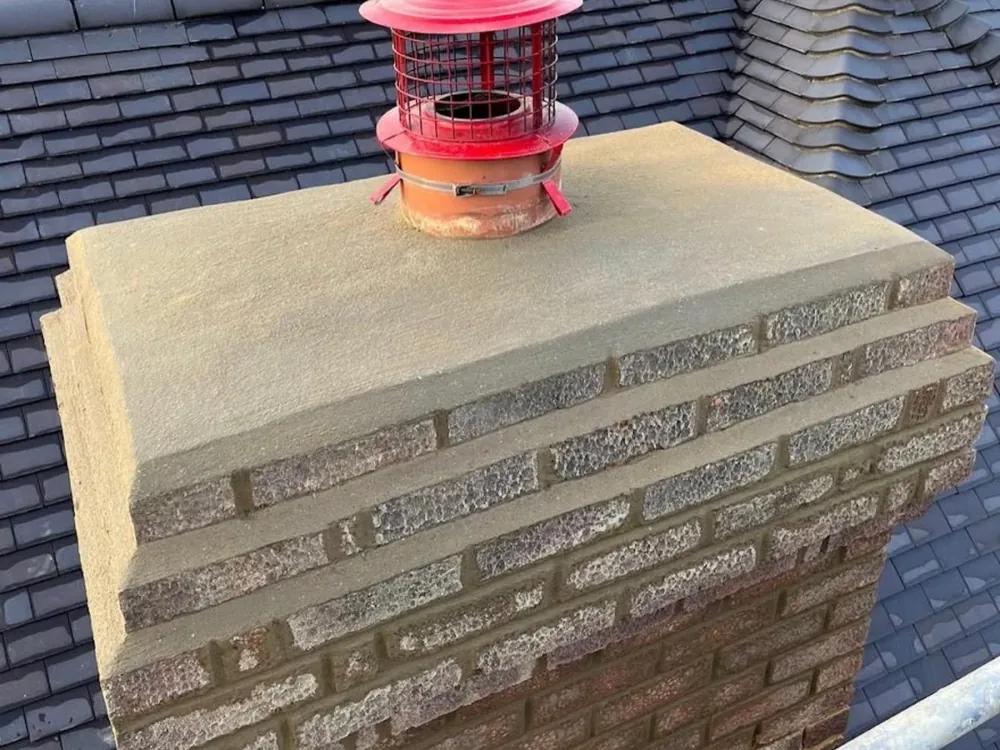Rebuilt chimney with a new stone cap and a red cowl