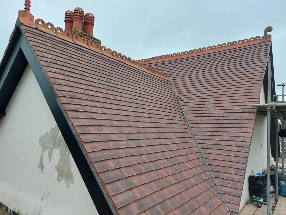 New plain tile roof meeting at a valley under a decorative ridge