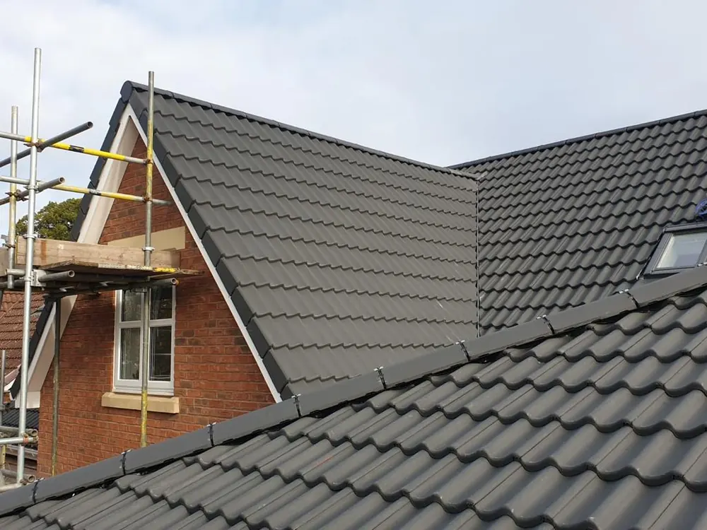 Grey interlocking tile re-roof on a gable house with the scaffold still up