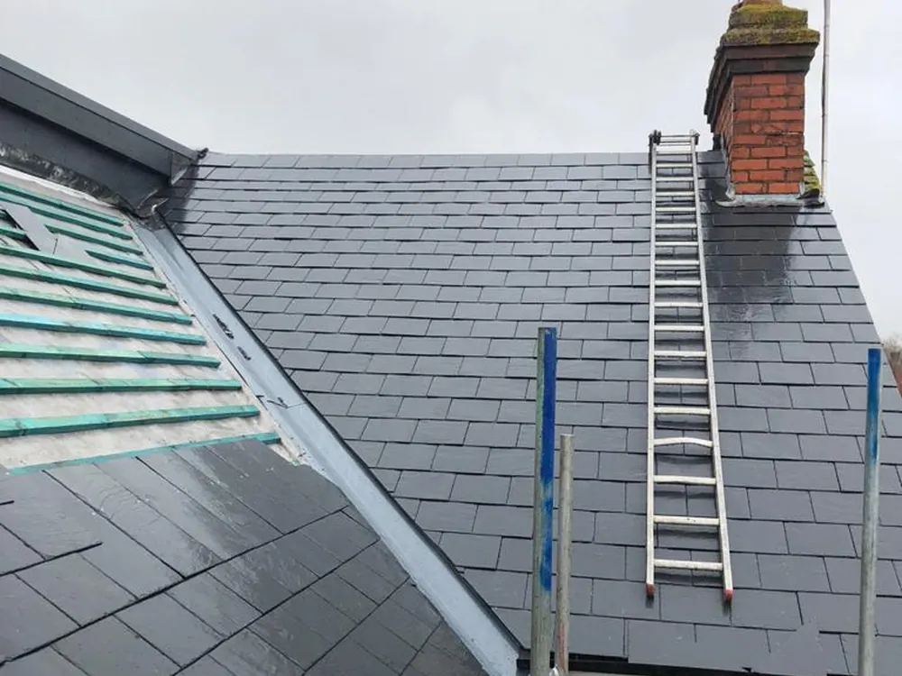 Slates going on over new battens and membrane, ladder in place