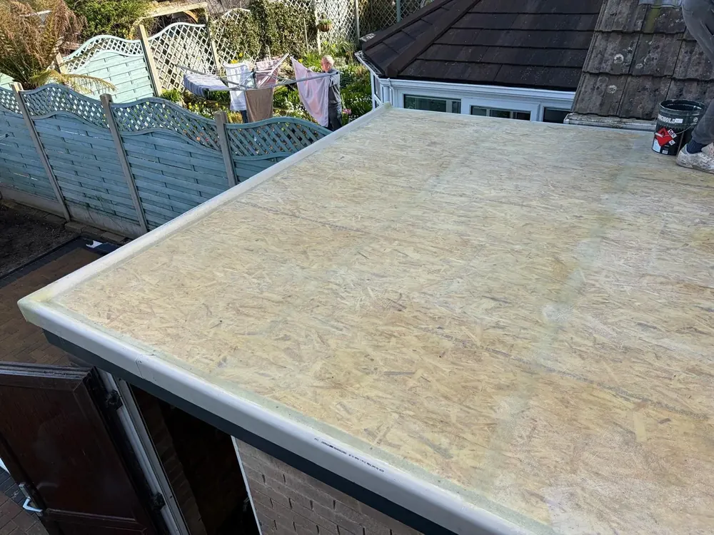 Fibreglass being laid over a flat roof deck with edge trims