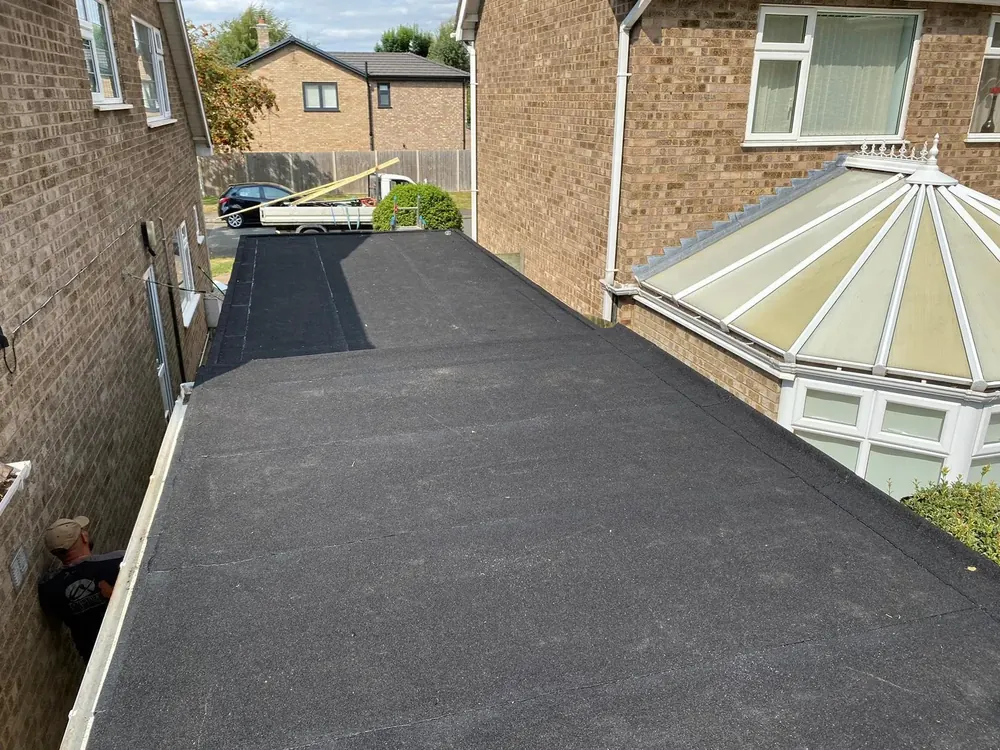Felt flat roof beside a brick house and conservatory