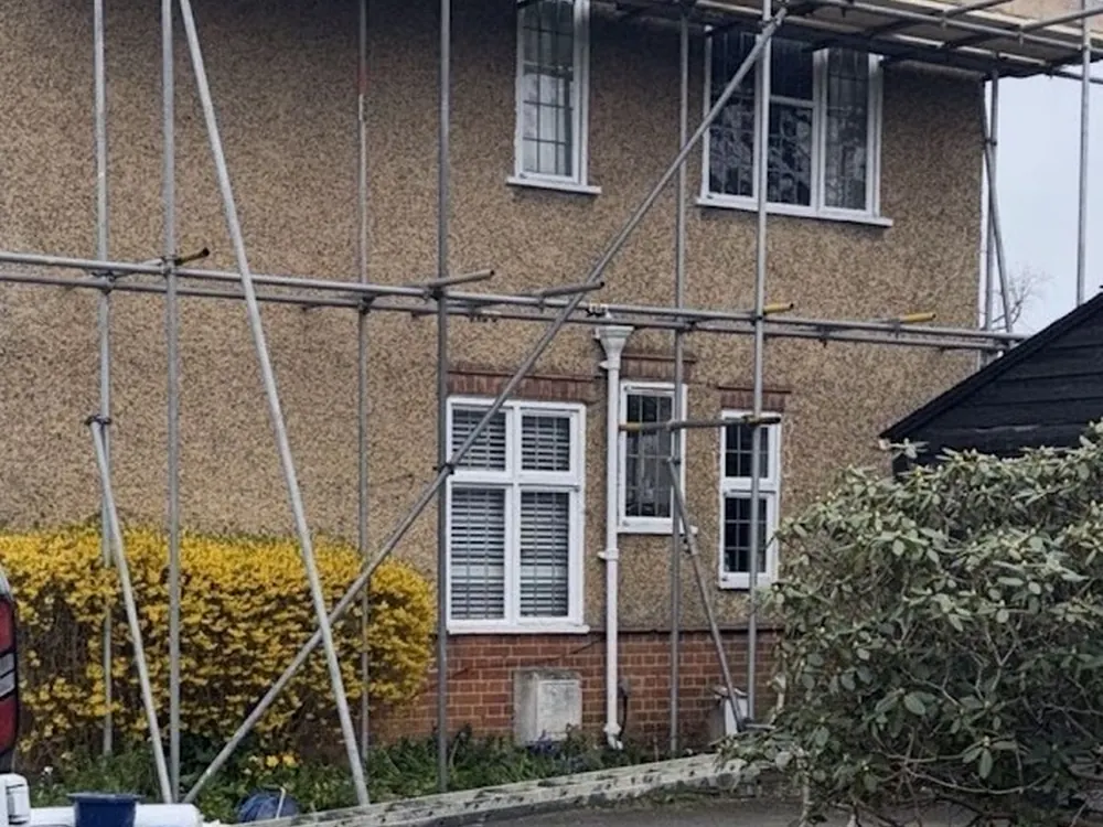 Full scaffold round a 1930s pebbledash semi during a re-roof