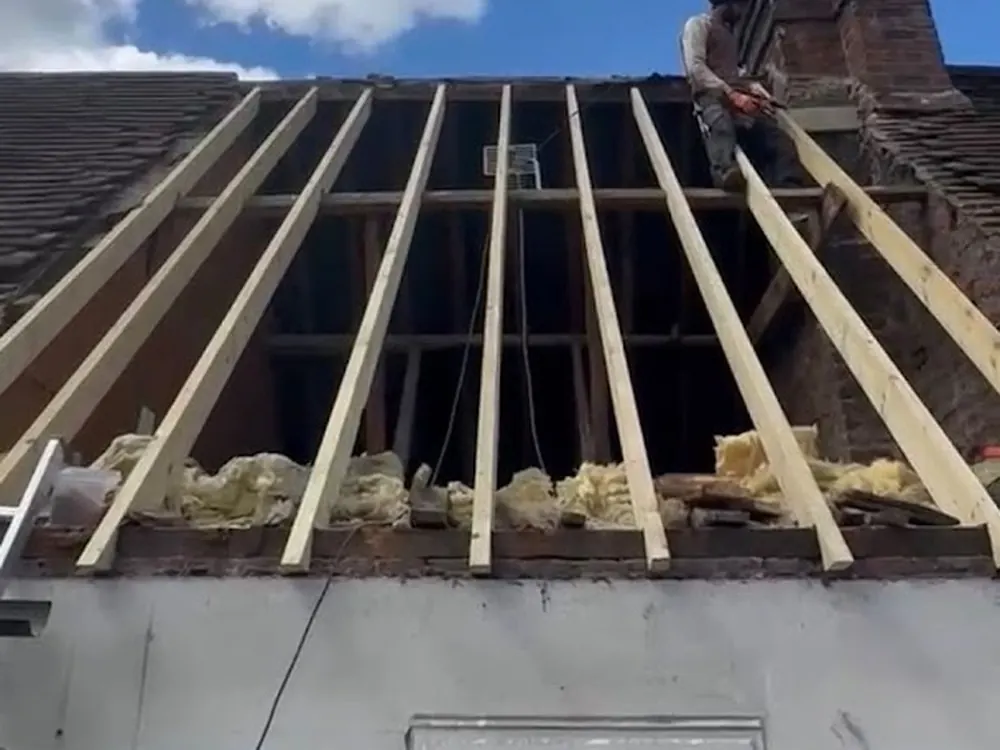 New rafters and insulation on an opened pitched roof beside the chimney stack