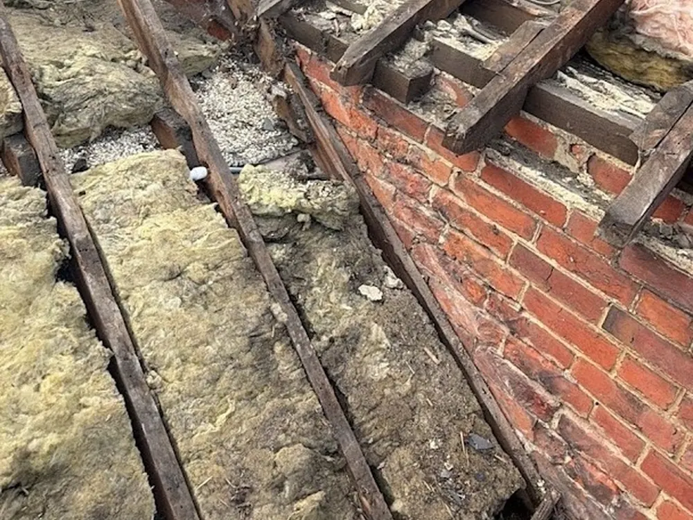 Rotten rafters and old insulation found under a stripped roof