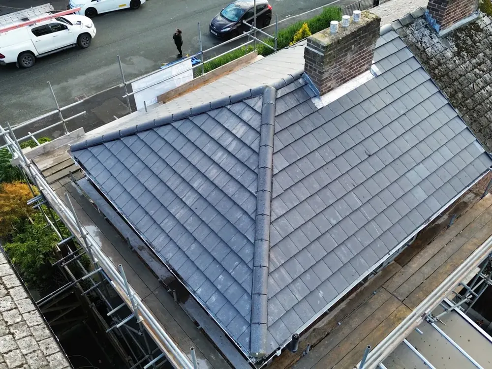Drone view of a new grey slate-effect hip roof with scaffold still up