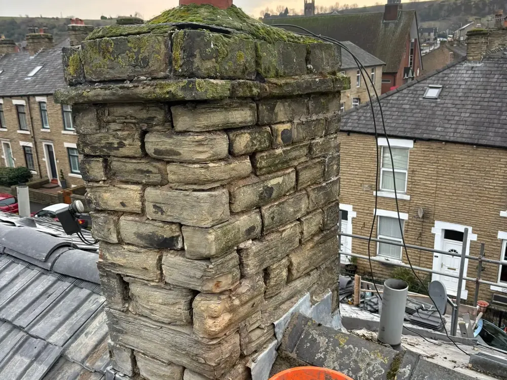 Stone chimney stack being repaired from the roof
