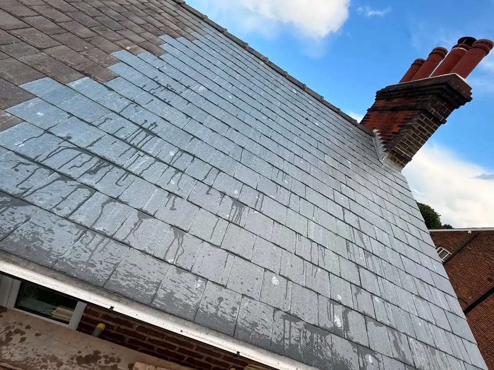 Finished slate roof and brick chimney against a blue sky