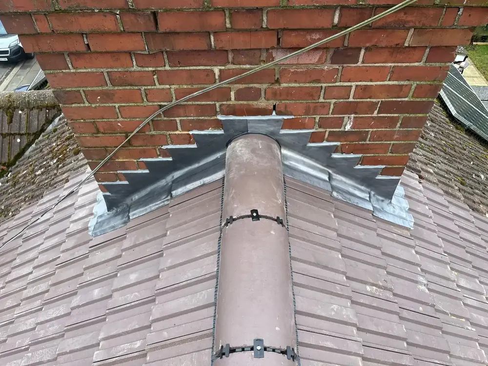 New ridge tiles meeting a new lead apron at the chimney