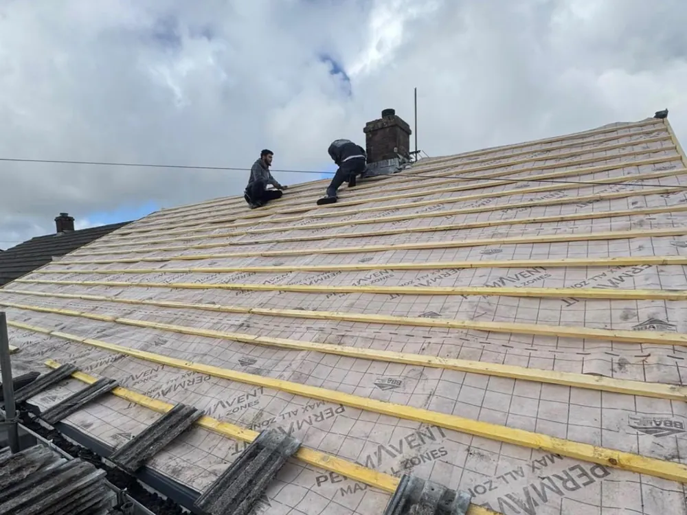 Roof stripped back to new breathable membrane and fresh battens, roofers at the ridge