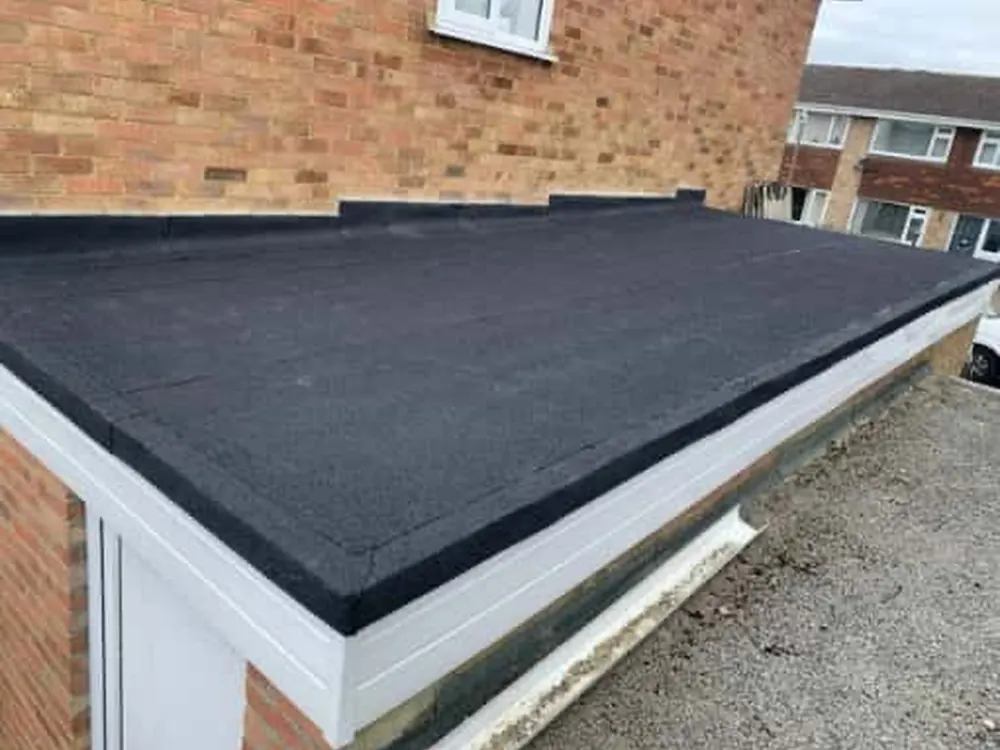 Felt flat roof with a new white fascia board on a brick extension