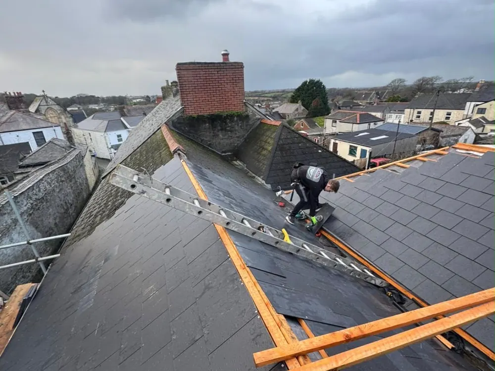 Roofer re-slating a terraced roof, with new battens laid out on the slates