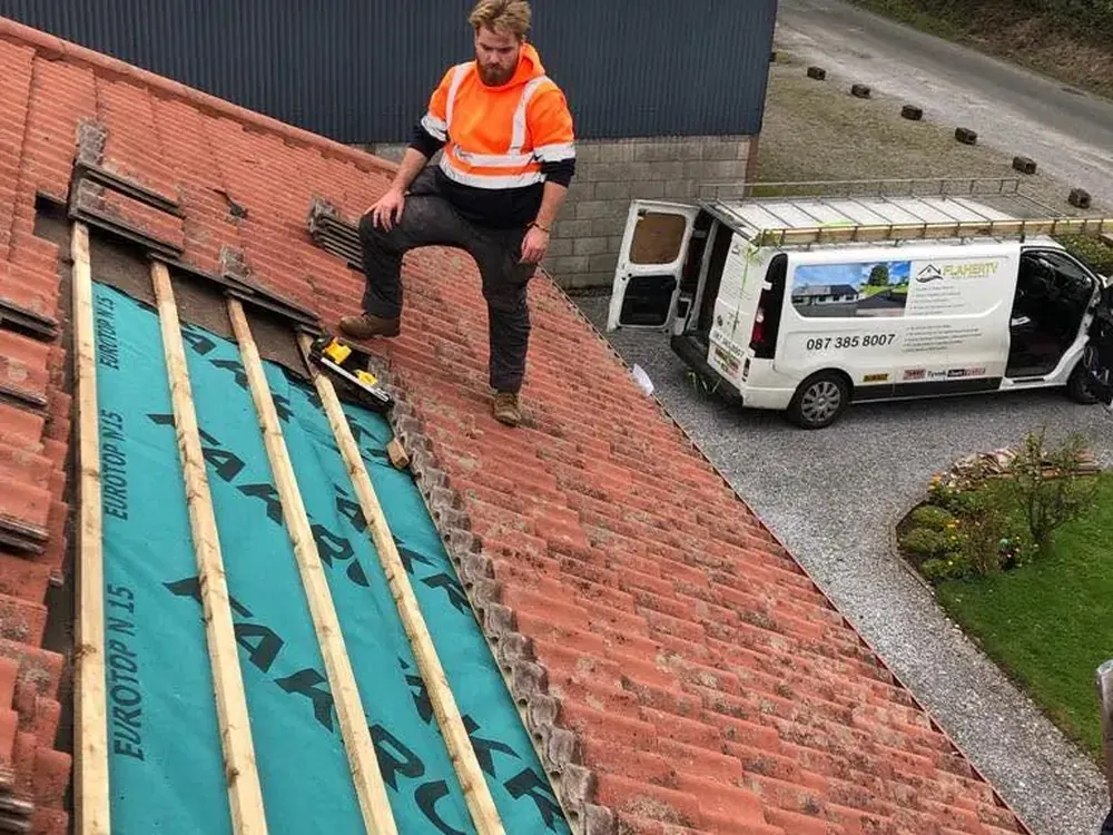 Roofer on new breathable membrane and battens with the Flaherty van parked below