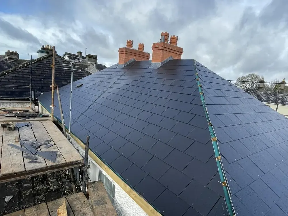 Finished hipped roof in new slate with brick chimneys