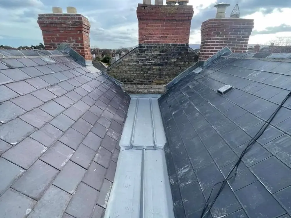 New lead valley running between two slate slopes below the chimneys