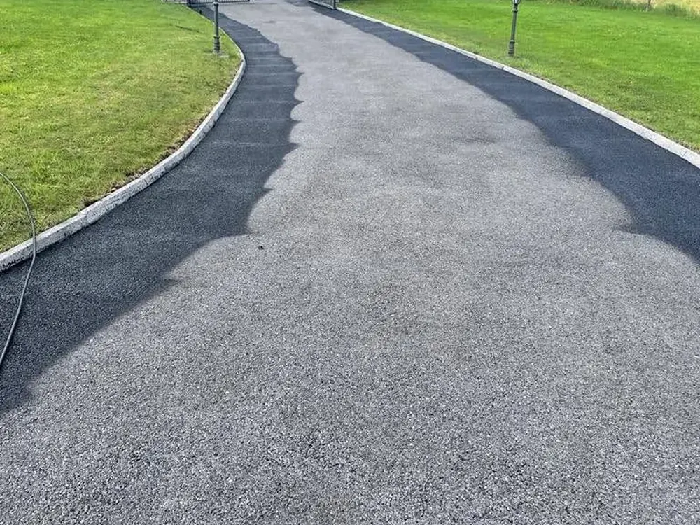 Long new tarmac driveway running through a country garden