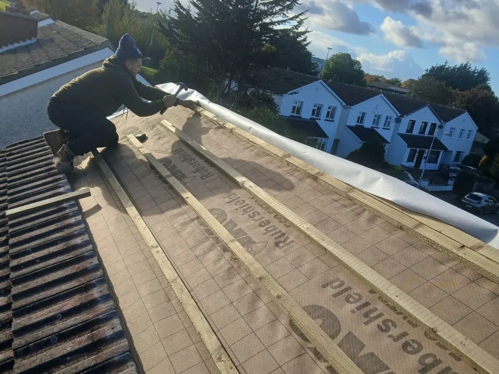 Roofer fixing new battens over breathable membrane on a concrete tile re-roof