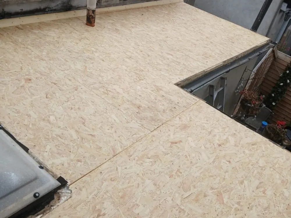 New OSB deck boarded over a flat roof extension beside a rooflight