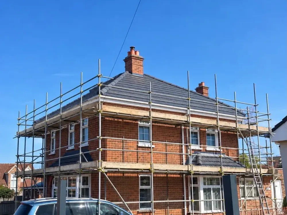 Two-storey brick house under scaffolding during a re-roof