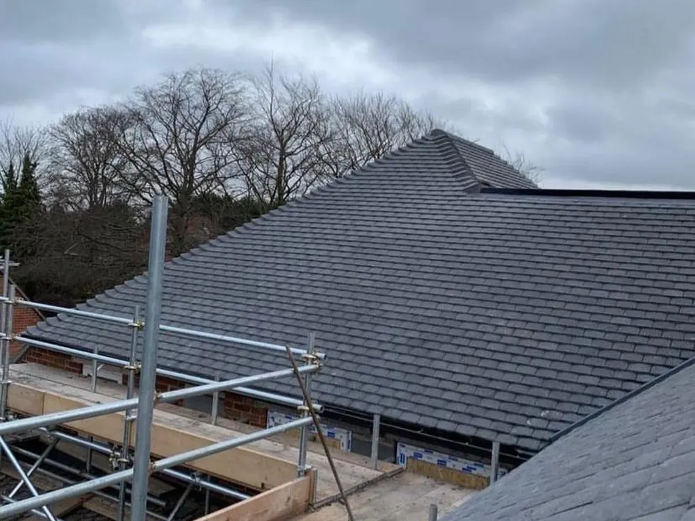 Completed grey hip roof seen from the scaffold