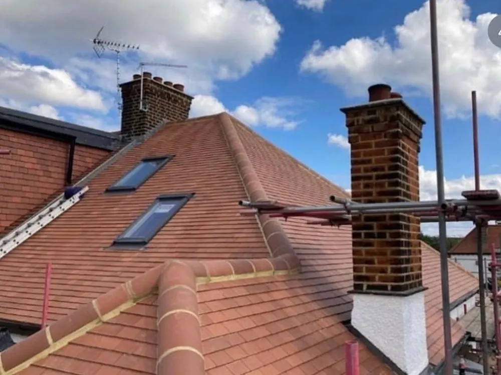 Red clay tile hip roof with rooflights and a brick chimney