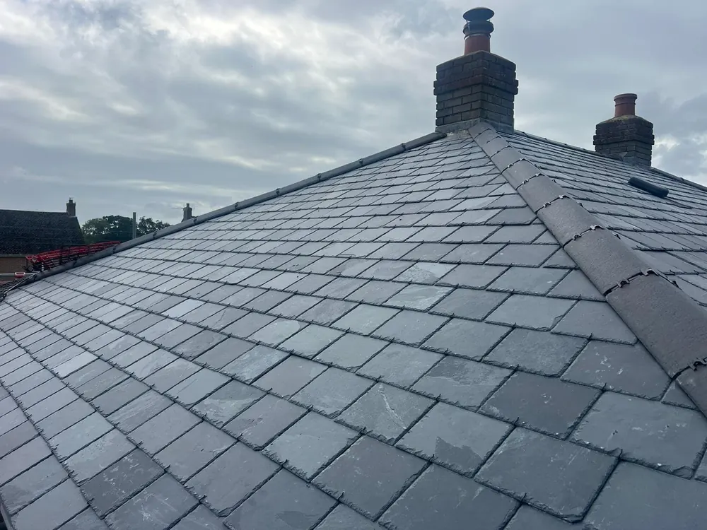 New slate hip roof finished with chimney stacks behind