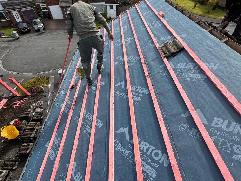 Roofer on a membrane-covered roof with red timber battens fixed across it