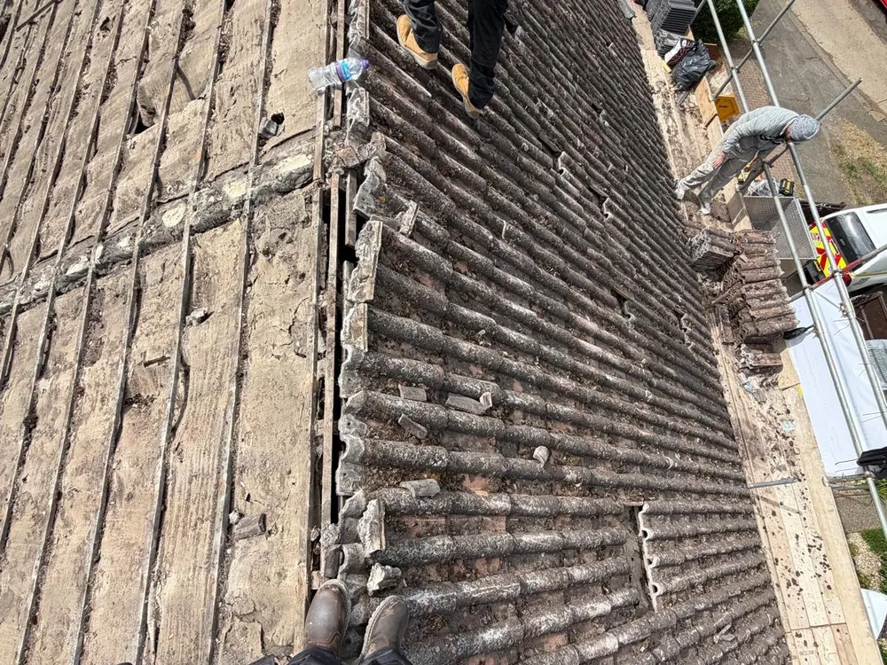 Old roof tiles being stripped off a pitched roof