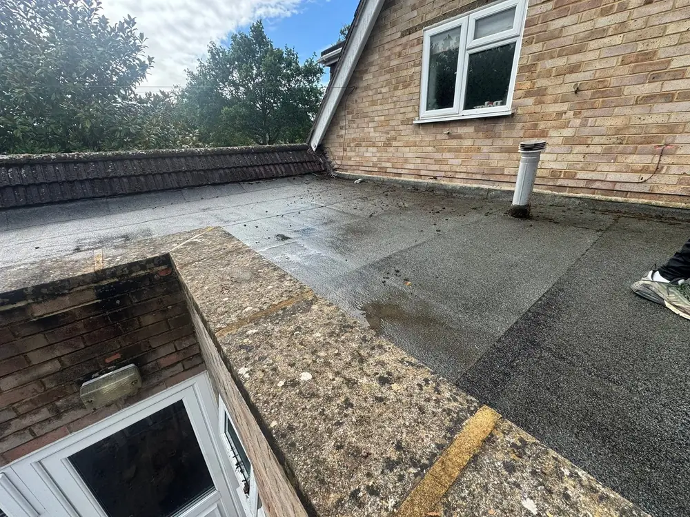 New torch-on felt flat roof beside a brick house with a white window in Bagshot