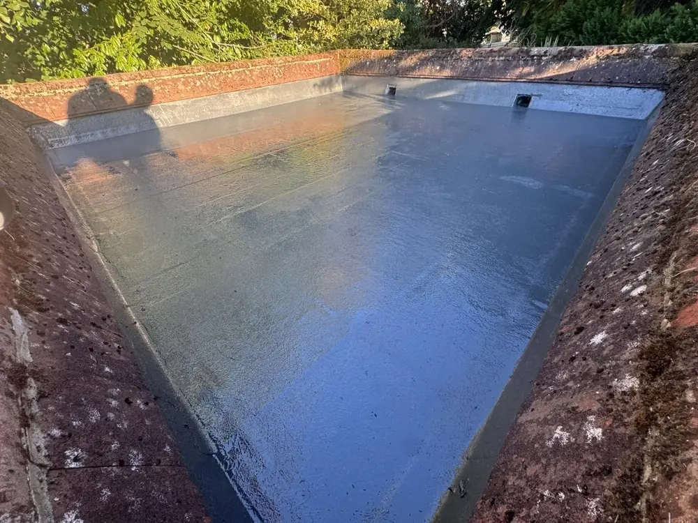 Finished grey GRP fibreglass flat roof with a brick parapet in Pirbright