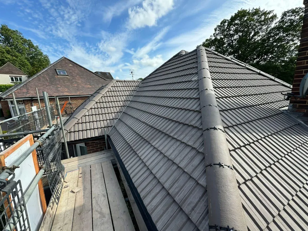 Grey interlocking tile hip roof finished with dry hip and ridge, scaffold still up